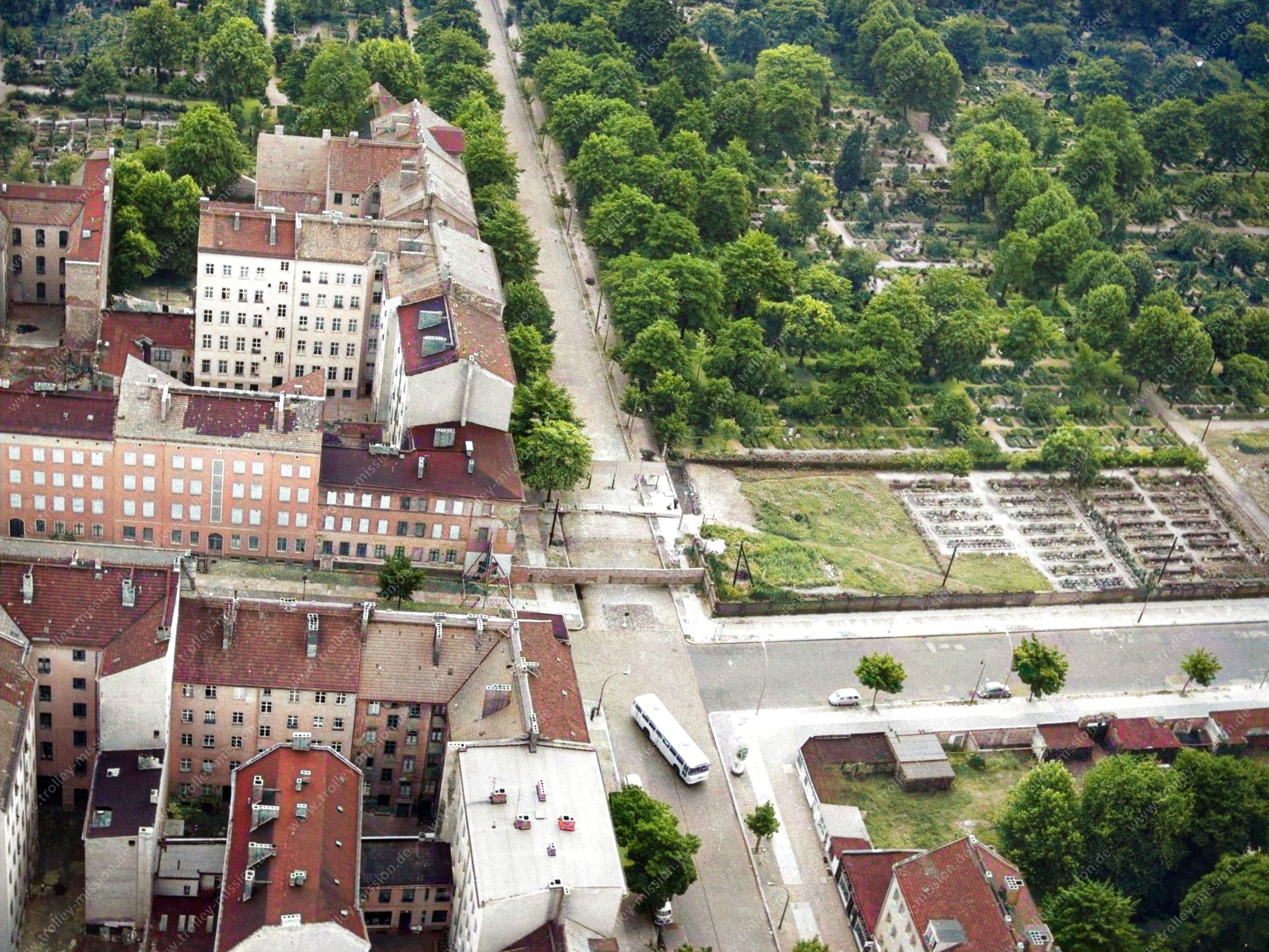 Die Luftaufnahme zeigt die Ackerstraße, die von unten nach oben durch das Bild verläuft und dabei die Bernauer Straße kreuzt.