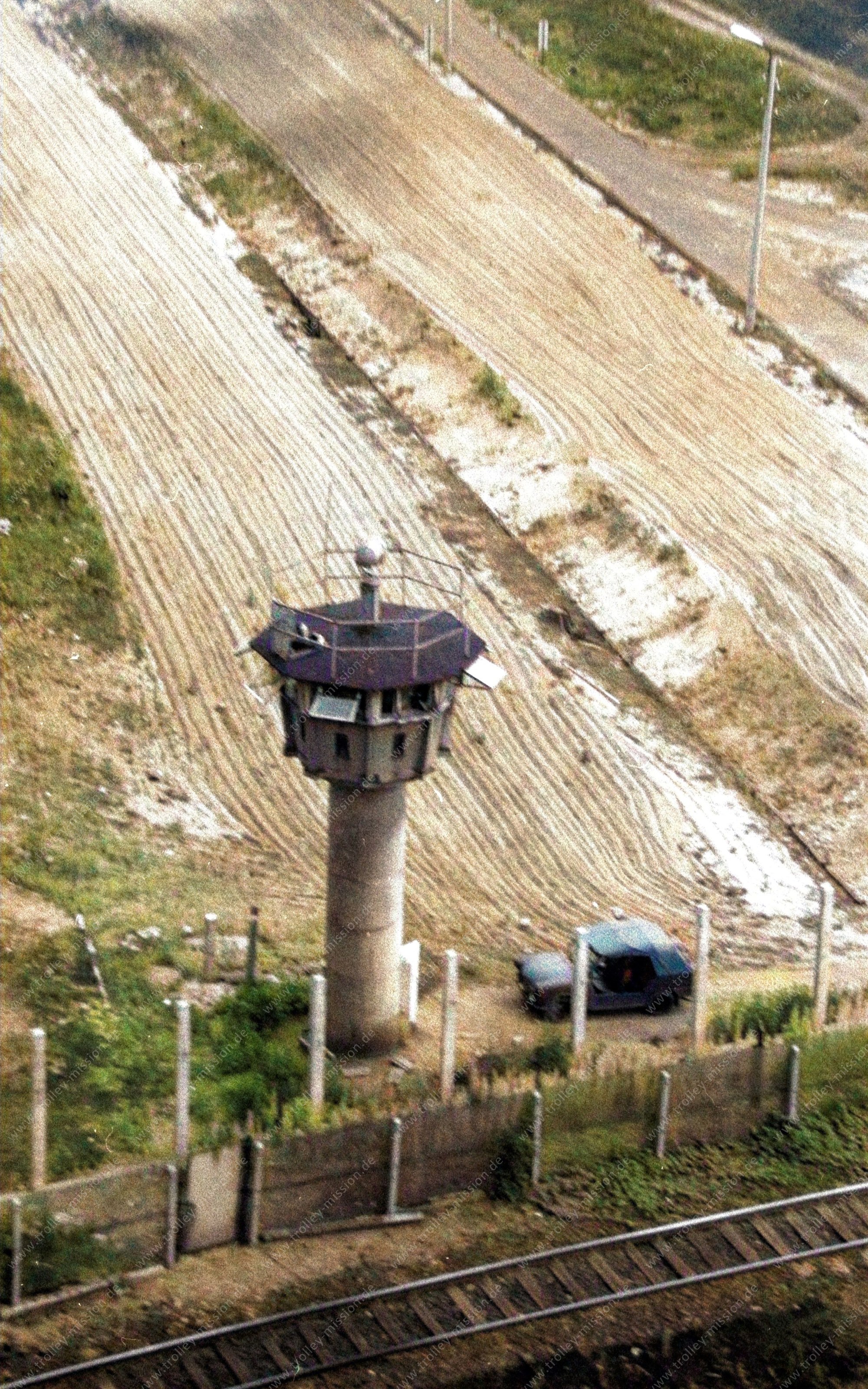 Die Luftaufnahme entstand am 9. März 1982 an den Grenzbefestigungsanlagen der Exklave Steinstücken. Auf dem Luftbild ist der niedrig gehaltene BT-9-Wachturm der Grenztruppen der DDR mit nur sechs Ringelementen zu sehen.